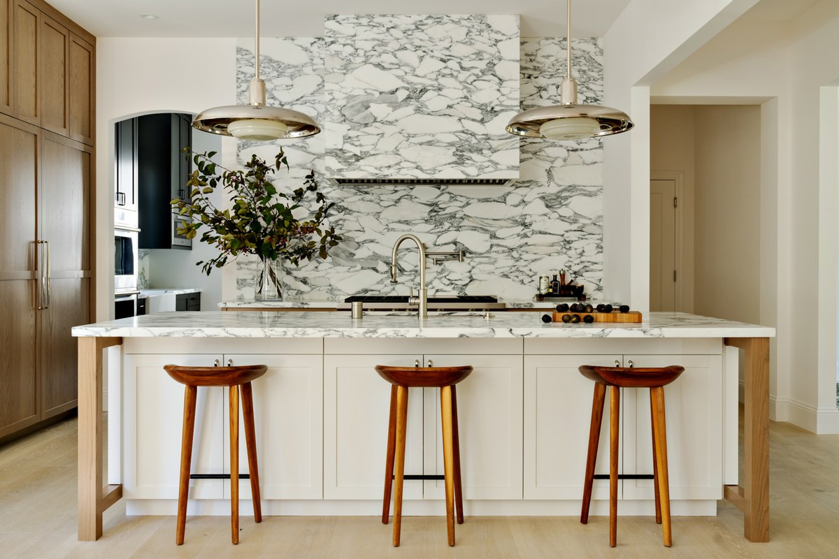 Sunlit modern kitchen showcasing veined natural marble and warm white oak cabinetry