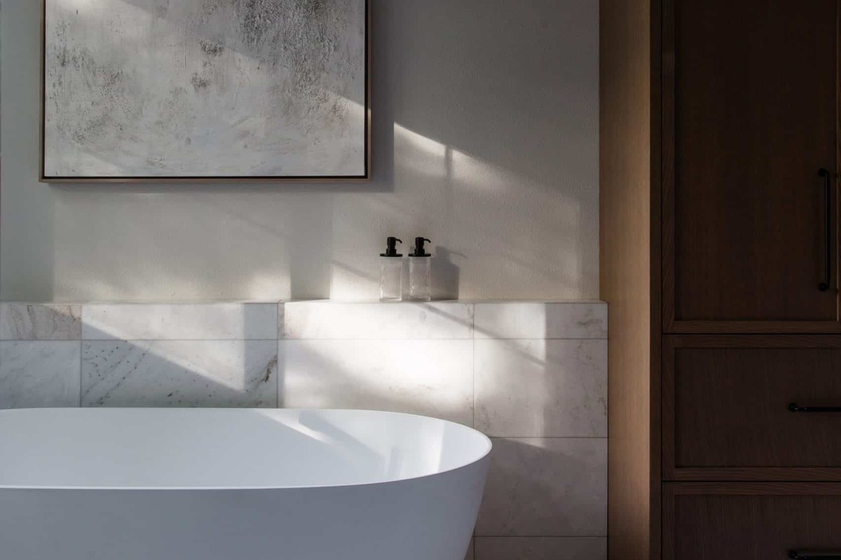 Spa-inspired remodeled bathroom with sculptural soaking tub, marble tile, and oak millwork